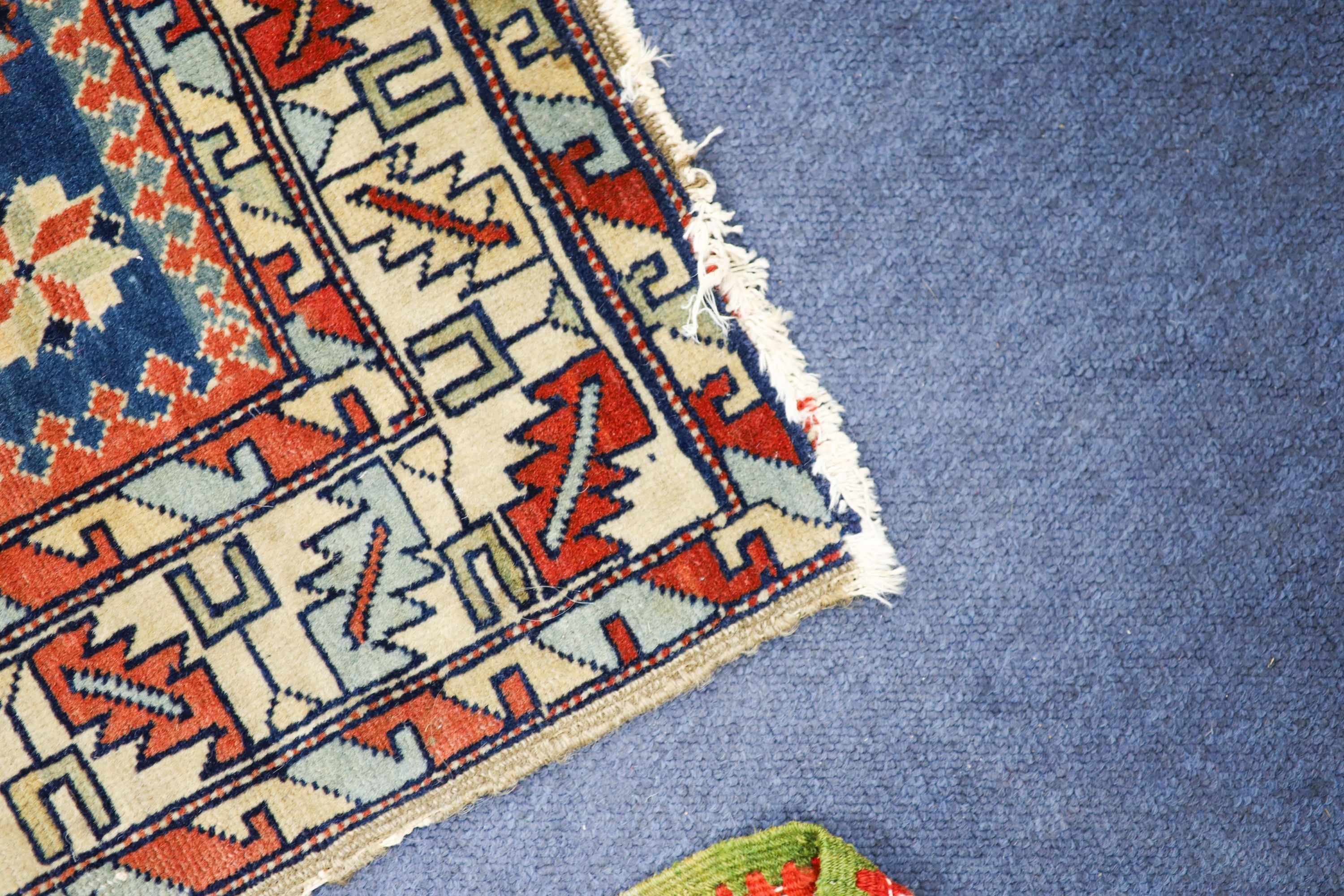 A Caucasian blue ground rug with triple medallions and geometric border, 144 x 89 cm.